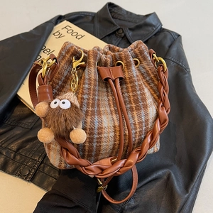 Sac seau rétro à carreaux avec poignée tressée et breloque en peluche sur fond cuir