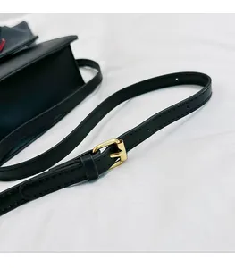 Détail macro d'une bandoulière en cuir noir avec boucle métallique dorée réglable