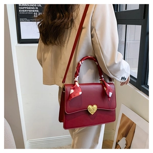 Détail du sac à main rouge vin en cuir avec boucle cœur dorée et foulard à pois chic