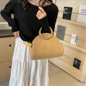 Semi-circular woven straw handbag with round handles and spiral texture in a cozy setting