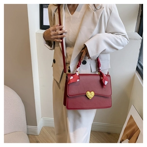 Détail du sac de mariage rouge avec fermoir cœur doré et poignée ornée d'un foulard