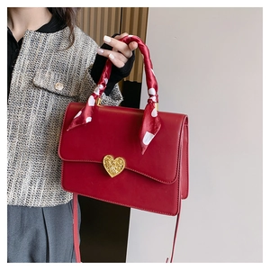 Détail du sac de mariage rouge avec boucle cœur dorée et poignée en foulard à pois