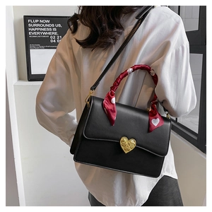 Détail du sac en cuir noir avec fermoir cœur doré et foulard décoratif à cœurs rouges