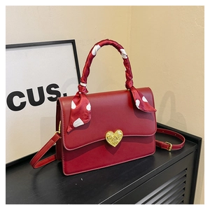 Détail du sac à main bordeaux avec fermoir cœur doré et foulard en soie à pois rouges