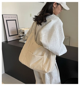 Detailed macro view of large beige nylon tote bag with functional exterior pocket