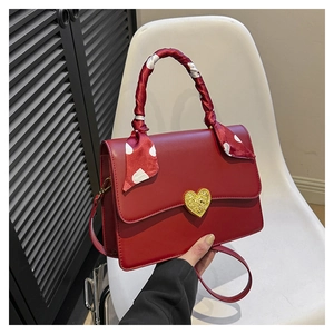 Détail d'un sac à main de mariage rouge avec fermoir coeur doré et foulard à pois