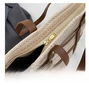 Detail shot of smooth golden metal zipper and brown leather trim on woven tote bag