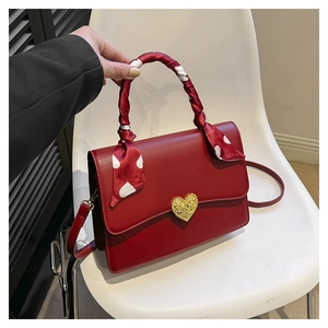 Détail du sac de mariée rouge avec fermoir cœur doré et foulard décoratif en soie enroulé