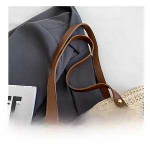 Detail of woven tote bag with brown leather strap and gold rivet reinforcement