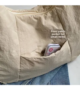 Detail view of beige nylon shoulder bag with front pocket for small items storage