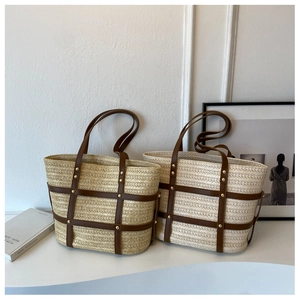 Close-up of woven straw tote bags with brown checkered leather trim and gold studs