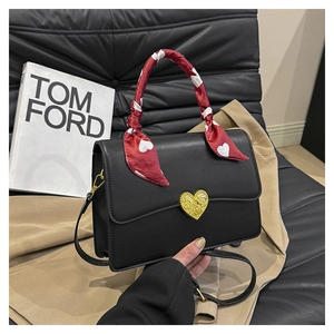 Détail du sac à main noir avec fermoir cœur doré et poignée décorée d'un foulard en soie