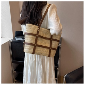 Fashion woven straw tote bag with brown leather straps shown on shoulder of a model