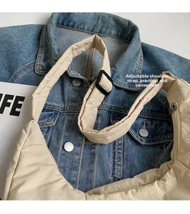 Detail showing the adjustable shoulder strap and plastic buckle on the beige nylon tote bag