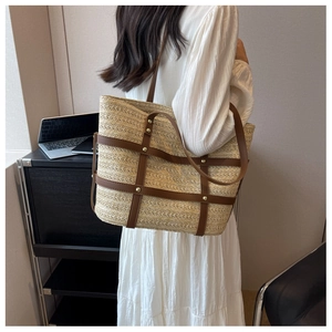 Macro detail of large straw tote bag with brown leather straps and gold rivets