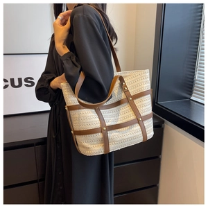 Detail of cream woven tote bag with brown leather straps and gold metal studs