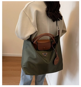 Détail du cabas en nylon vert olive avec poignées en cuir et logo triangle en métal