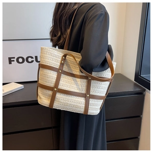 Close-up of woven tote bag with brown leather straps and gold rivets shown on a model