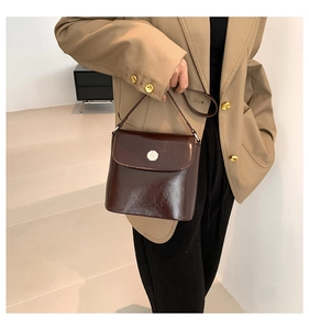 Detail van elegante donkerbruine leren handtas met zilveren gesp over de schouder gedragen