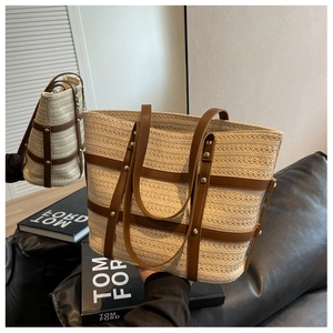 Detail of straw tote bag featuring brown PU leather trim and gold rivet studs
