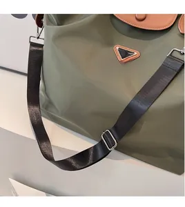 Détail de la bandoulière réglable et du logo métallique sur le sac fourre-tout vert