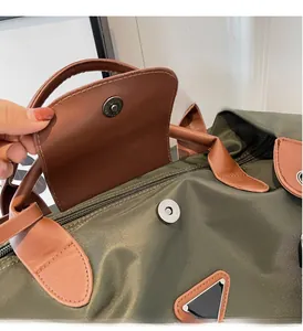 Détail du sac cabas en nylon vert armée avec bordure en cuir marron et plaque triangulaire