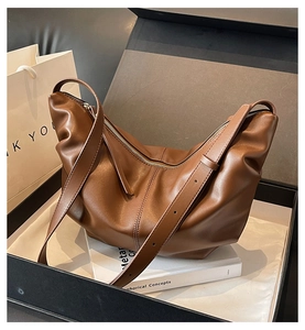 Dettaglio della borsa a mezzaluna marrone pieghettata in un elegante pacchetto regalo nero