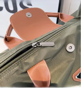 Détail du sac cabas en nylon vert armée avec poignée en cuir brun et fermeture éclair