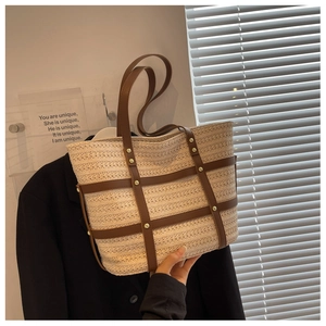 Detail of woven straw tote bag with brown leather trim and vintage gold studs