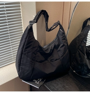 Close-up of black quilted nylon tote bag with adjustable strap in soft window light