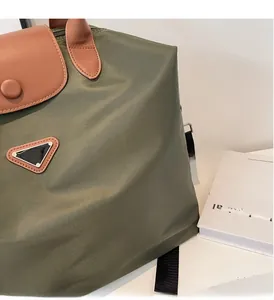 Gros plan d'un sac cabas en nylon vert avec poignées en cuir marron et logo triangle