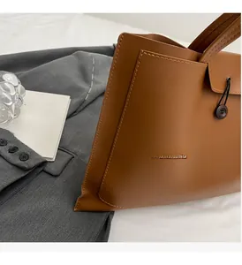 Detail of a brown leather tote bag with a wooden button closure and fine stitching