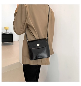 Glanzende zwarte crossbodytas gestyled met een kaki oversized blazer voor damesmode