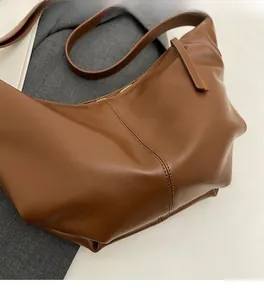 Dettaglio di una borsa a tracolla plissettata marrone scuro con trama in ecopelle