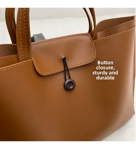 Detail view of the brown leather tote bag showing the button closure and durable stitching