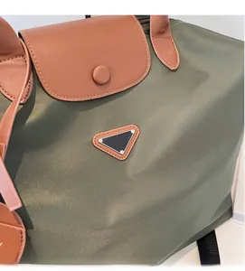 Détail du sac cabas en nylon vert olive avec rabat en cuir marun et logo triangle en métal