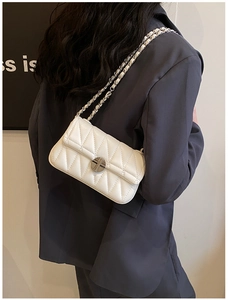 Detailansicht der weißen Stepptasche mit goldener Kette an einem weiblichen Model