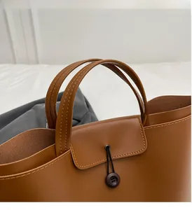 Detail of a brown PU tote bag showing wood button closure and textured handles