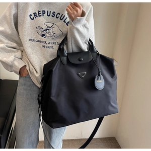 Modèle portant un grand sac cabas en nylon noir avec poignées en cuir et bandoulière réglable