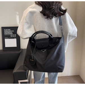 Détail du cabas noir en nylon avec bandoulière large réglable et logo triangulaire chic