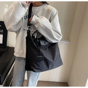 Détail du sac cabas en nylon noir avec rabat en cuir et bandoulière réglable amovible