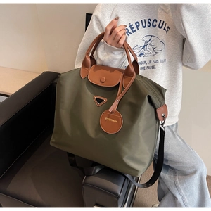 Détail du grand sac cabas en nylon avec poignées en cuir et logo triangle en métal