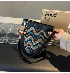 Detail of knit bucket bag with wave patterns, leather trim, and cute plush charm