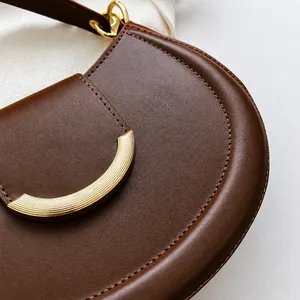 Detail einer braunen Leder-Achseltasche mit goldener Schließe und präzisen Nähten
