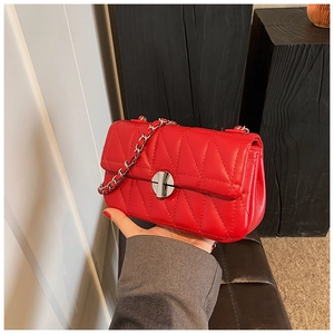 Details der roten Stepptasche mit silberner Metallkette und rundem Drehverschluss
