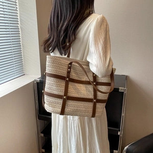 Large capacity woven tote bag with brown leather straps shown on model in room