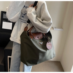 Vue détaillée du grand cabas en nylon vert olive avec anses en cuir marron et logo métal