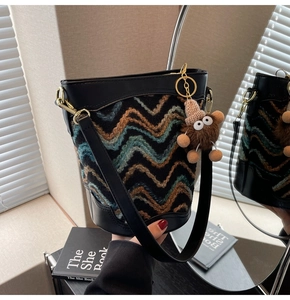 Close-up of retro bucket bag featuring rainbow herringbone weave and plush charm