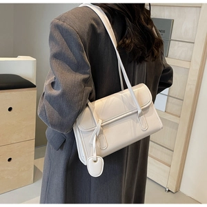Detail of white glossy underarm bag showing the patent leather texture and heart pendant
