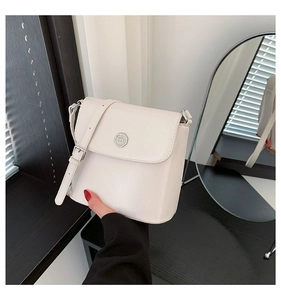 Detail van witte leren crossbody tas met een zilveren metalen gesp en verstelbare schouderband